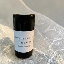 Load image into Gallery viewer, Solid lotion stick labeled 'Bali Breeze' by 'Vintage Alchemy' on a textured surface.