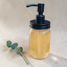 Load image into Gallery viewer, amber glass soap dispenser with matte black pump on warm stone surface with eucalyptus botanical styling