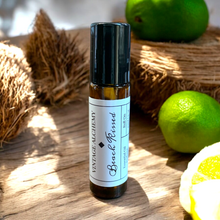 Load image into Gallery viewer, Beach Kissed coconut citrus perfume oil in 10ml amber glass roller bottle on wood with fresh lime and coconut background