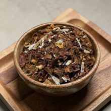 Load image into Gallery viewer, loose leaf coconut chocolate tea blend with cacao shells and coconut flakes in ceramic bowl on wood tray