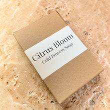 Load image into Gallery viewer, Bar of Citrus Bloom cold process soap on a textured beige surface