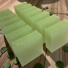 Load image into Gallery viewer, Green soap bars on a wooden surface with green leaves.