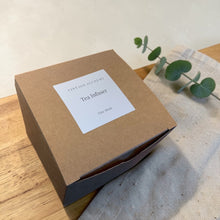 Load image into Gallery viewer, Vintage Alchemy loose leaf tea infuser packaging box on wood surface with linen cloth and eucalyptus branch