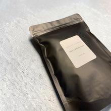Load image into Gallery viewer, Mineral Bath Soak in matte black resealable pouch with minimalist label on light stone background