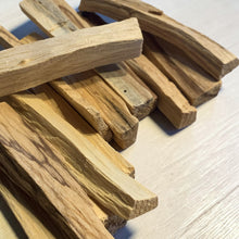 Load image into Gallery viewer, Palo Santo wood sticks stacked on light wood tabletop for ritual burning and aromatic use
