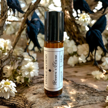 Load image into Gallery viewer, Raven’s Claw perfume oil in 10ml amber glass roller bottle on textured wood with moody botanical background
