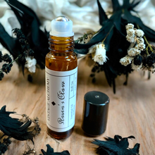Load image into Gallery viewer, Raven’s Claw essential oil perfume with stainless steel roller ball applicator and cap beside bottle on natural wood surface