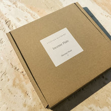 Load image into Gallery viewer, Sheesam wood incense plate packaged in kraft box with Vintage Alchemy label on warm mineral surface