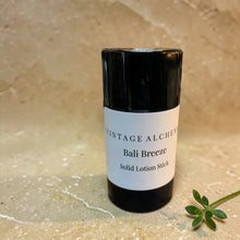 Load image into Gallery viewer, Bali Breeze solid lotion stick on warm limestone surface with small green sprig