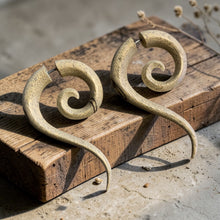 Load image into Gallery viewer, handcrafted spiral wood earrings resting on weathered wooden board with soft botanical background