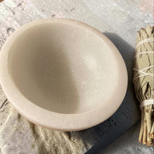 Load image into Gallery viewer, White marble smudge bowl displayed on a textured stone surface beside a bundled sage smudge stick.