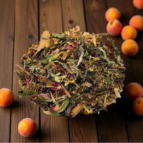 Dry herbs in a wooden bowl with peaches on a wooden surface