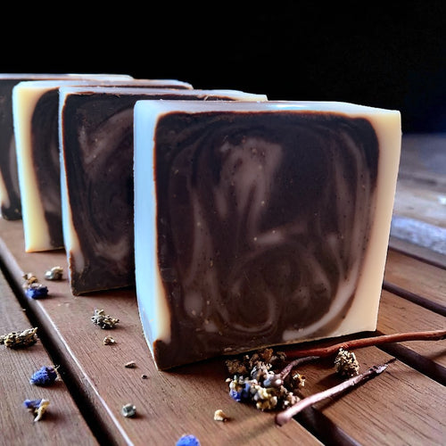 Swirl-patterned soap bars on a wooden surface with dried flowers and twigs.