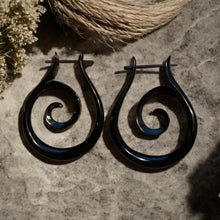 Load image into Gallery viewer, Black spiral earrings on a textured surface with natural elements.
