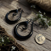 Load image into Gallery viewer, Black hoop earrings on a wooden surface with twine and flowers
