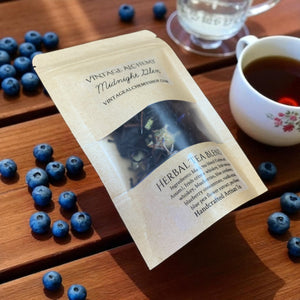 Herbal tea blend package with blueberries and a cup of tea on a wooden surface