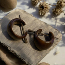 Load image into Gallery viewer, Pair of wood moon-shaped earrings on a stone surface with dried plants in the background.
