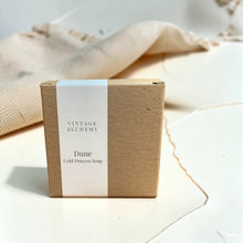 Load image into Gallery viewer, Vintage Alchemy Dune cold process soap in kraft packaging with minimalist white label on a soft plaster surface with linen backdrop.

