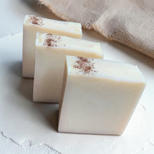 Load image into Gallery viewer, Three bars of Dune cold process soap with a creamy ivory finish and cocoa-dusted tops on a soft plaster surface with natural linen accents.

