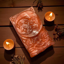 Load image into Gallery viewer, Decorative moon design soap on a wooden surface with candles and herbs.
