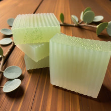Load image into Gallery viewer, Two green soap bars on a wooden surface with leaves in the background
