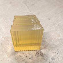 Load image into Gallery viewer, translucent glycerin soap lemon verbena citrus bar with golden tone on neutral limestone background
