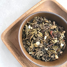 Load image into Gallery viewer, white bloom jasmine apple green and black loose leaf teas in a ceramic bowl on a wood tray

