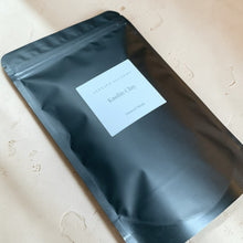 Load image into Gallery viewer, Kaolin clay mineral mask in matte black pouch with minimalist Vintage Alchemy label on neutral plaster surface
