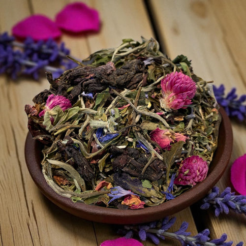 Herbal tea mix with flowers in a brown bowl on a wooden surface