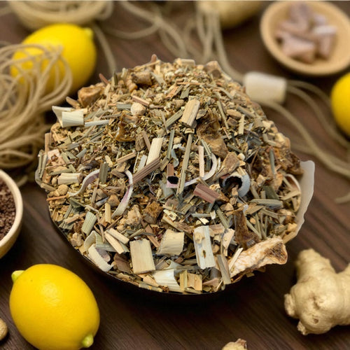 Bowl of herbal tea blend with lemons and ginger on a wooden surface