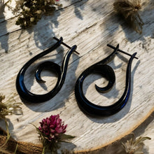 Load image into Gallery viewer, Black spiral earrings on a wooden surface with dried flowers.
