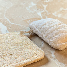 Load image into Gallery viewer, Natural loofah sponge shown dry and expanded on warm stone surface, plant-based kitchen dish scrubber that softens when wet
