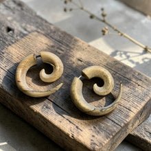 Load image into Gallery viewer, Natural spiral wood fake gauge tribal earrings displayed on weathered wood block with soft botanical background in natural light

