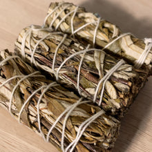 Load image into Gallery viewer, Peppermint and sage smudge bundles tied with cotton cord on wood tabletop by Vintage Alchemy

