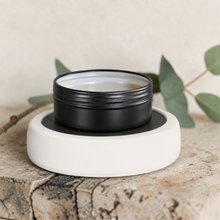 Load image into Gallery viewer, White plate warmer with black Apothecary Dish for flame-free fragrance on weathered stone surface with soft eucalyptus styling
