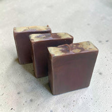 Load image into Gallery viewer, Three bars of Pyre Dragon’s Blood soap with rich brown coloring and natural tan swirls on a stone gray background.
