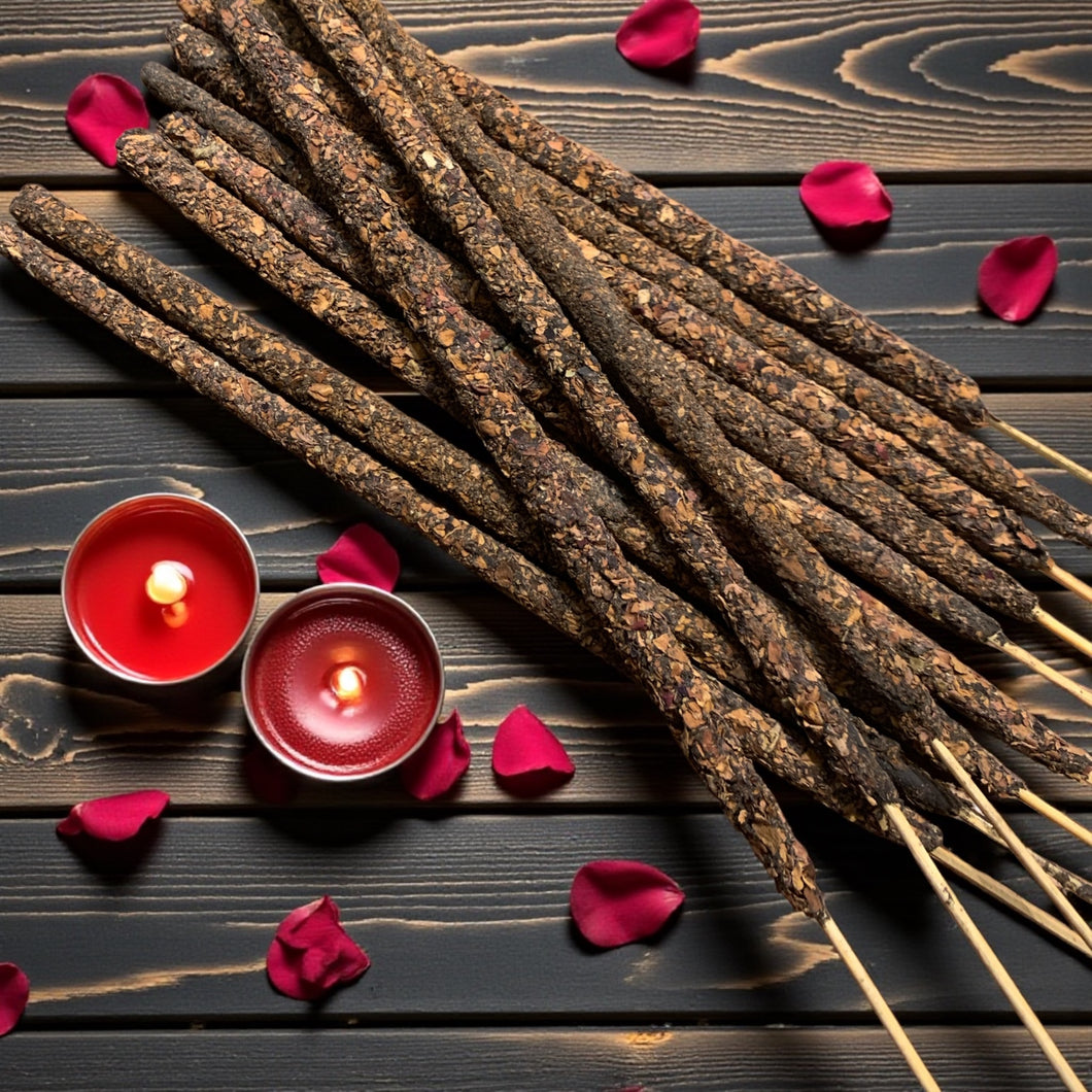 Incense sticks with red candles and rose petals on a wooden surface