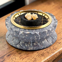 Load image into Gallery viewer, Carved stone incense burner with brass screen holding charcoal and resin incense on wood surface
