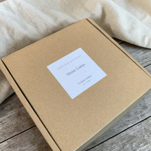 Load image into Gallery viewer, Stone lotus tealight holder packaged in kraft gift box with Vintage Alchemy label on weathered wood surface with linen backdrop
