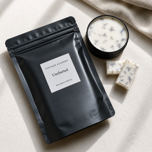 Load image into Gallery viewer, Uncharted botanical wax melt refill pouch beside black apothecary wax melt dish with lavender botanical soy wax melts on soft stone surface
