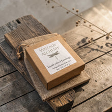 Load image into Gallery viewer, Vintage Alchemy handcrafted earrings gift box with linen pouch displayed on weathered wood with soft botanical background
