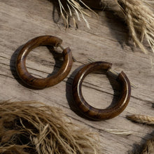 Load image into Gallery viewer, Wooden hoop earrings on a rustic wooden surface with natural elements.
